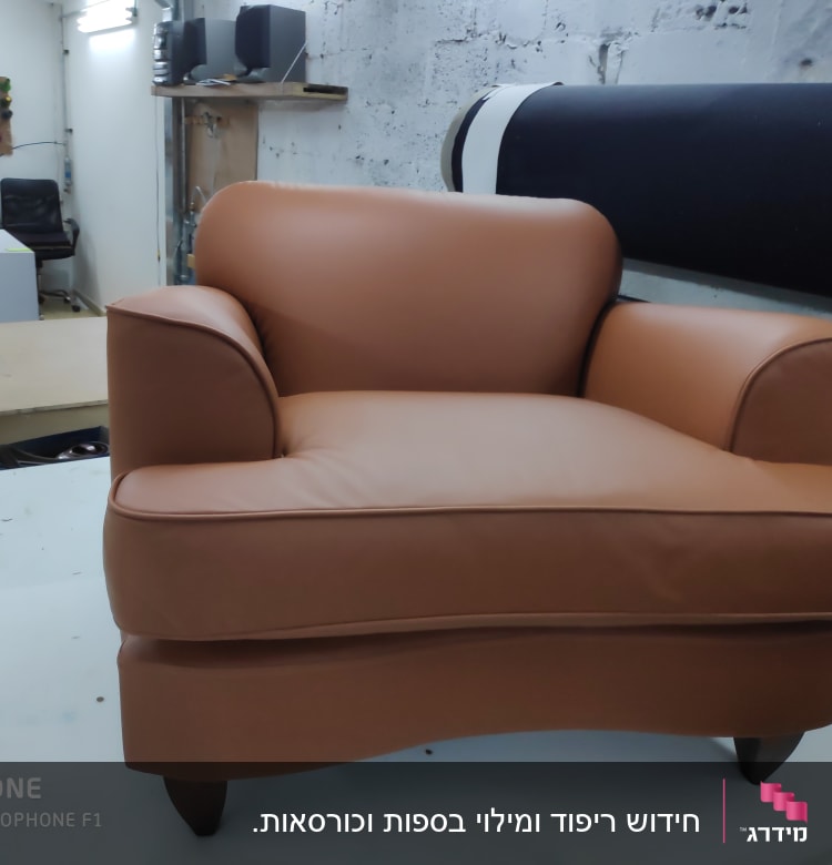 כורסה מרופדת בעור חום בסטודיו לריפוד